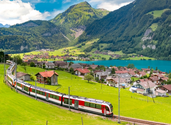 A train travels through a Swiss valley and Lake