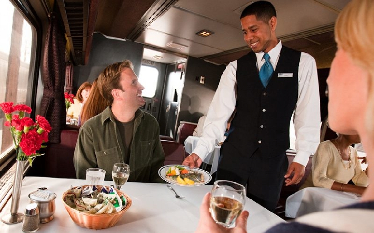 Waiter helping people onboard Amtrak in Dining car