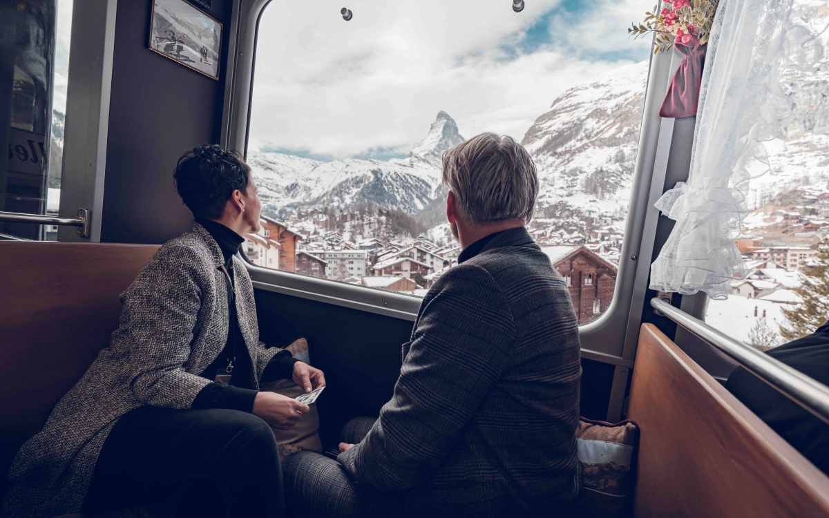 a couple sitting in nostalchic class onboard the gornergrat looking out the window in winter