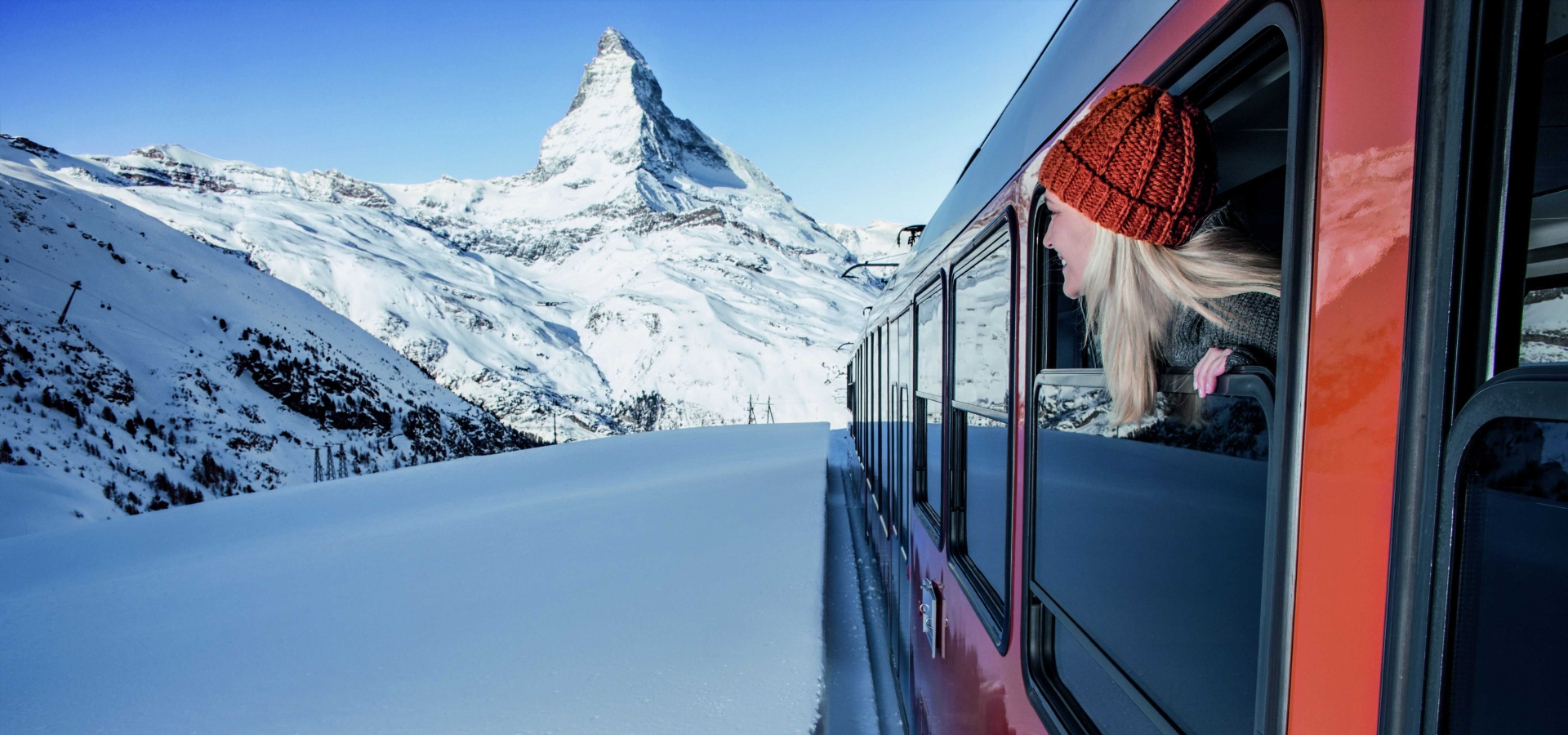 A train travels through snowy landscape towards Matterhorn