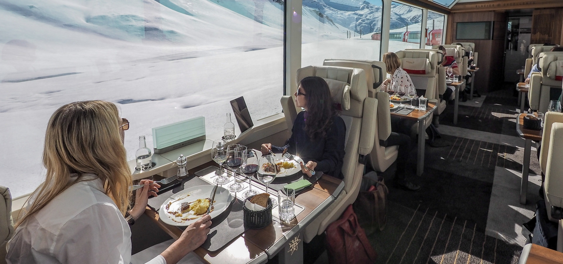 Train travellers look out of the window and the snowy Alpine scenery