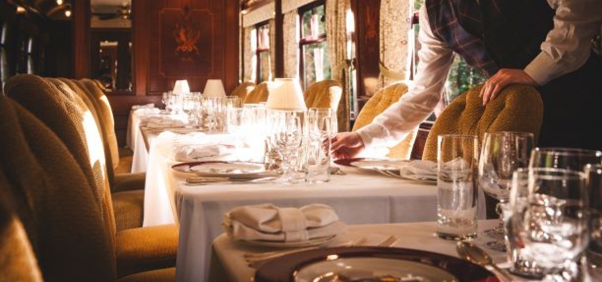 A waiter lays the table ready for dinner onboard the train