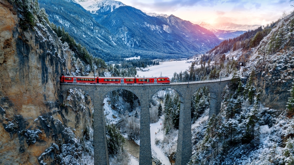 Aerial view of Train passing through famous mountain in Filisur, Switzerland train express in Swiss Alps snow winter scenery.