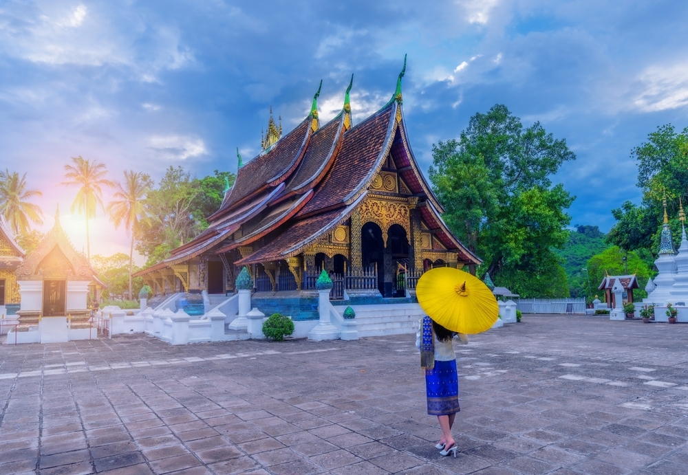 Asian woman wearing a Lao national costume visits Wat Xieng Thong in Luang Prabang, Laos